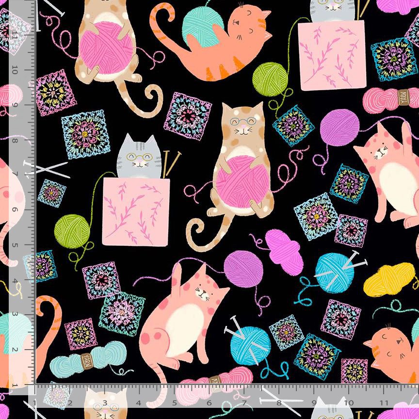 A repeating fabric pattern featuring playful cats holding balls of pink, teal, and purple yarn, surrounded by colorful knitted square motifs on a black background, with a ruler visible along the left and bottom edges. Available at Sewing Bee Studio.