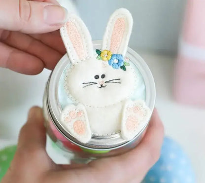 Person holding a small container with a decorative rabbit figure on top