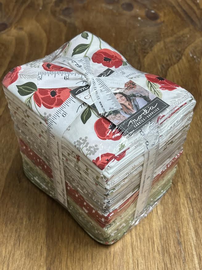 Bundle of fabric fat quarters with floral designs labeled as Christmas Eve by Moda. Sewing Bee Studio.