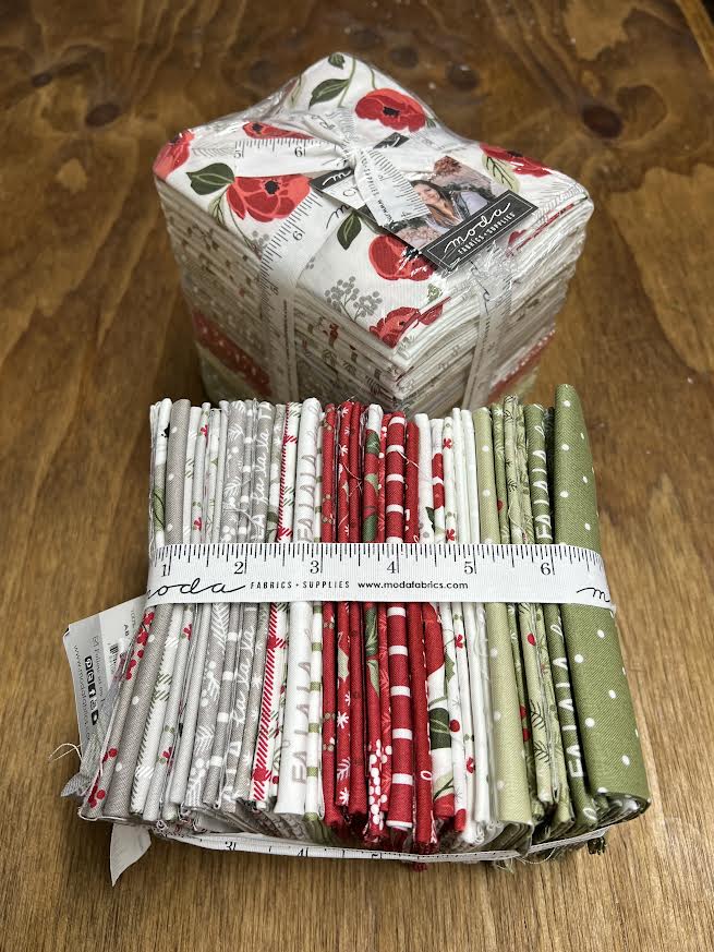 Bundles of fabric fat quarters with a measuring tape on a display table in Sewing Bee Studio.
