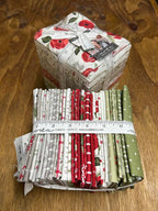 Bundles of fabric fat quarters with a measuring tape on a display table in Sewing Bee Studio.