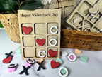 Valentine's Day-themed wooden game with hearts and circles on a marble surface.