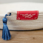 Textile product with a red label and blue tassel on a wooden surface (Sewing Bee Studio)