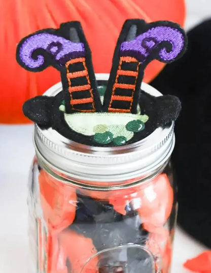 Mason jar with witch's legs decoration on a white background