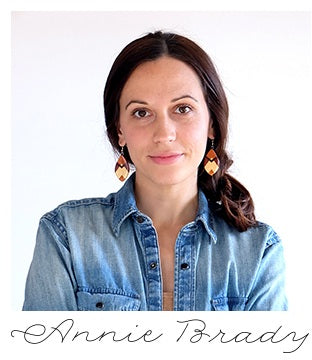 Designer wearing a denim shirt with a plain background.