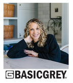 Designer sitting at a table in a home setting with Basic Grey logo. Sold by Sewing Bee Studio.