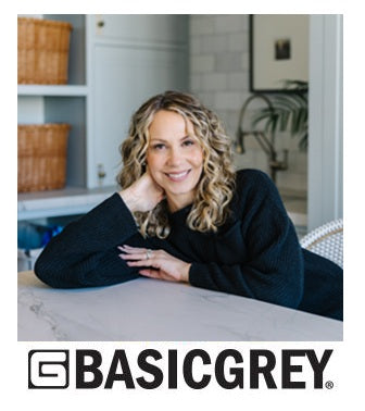 Designer sitting at a table in a home setting with Basic Grey logo. Sold by Sewing Bee Studio.