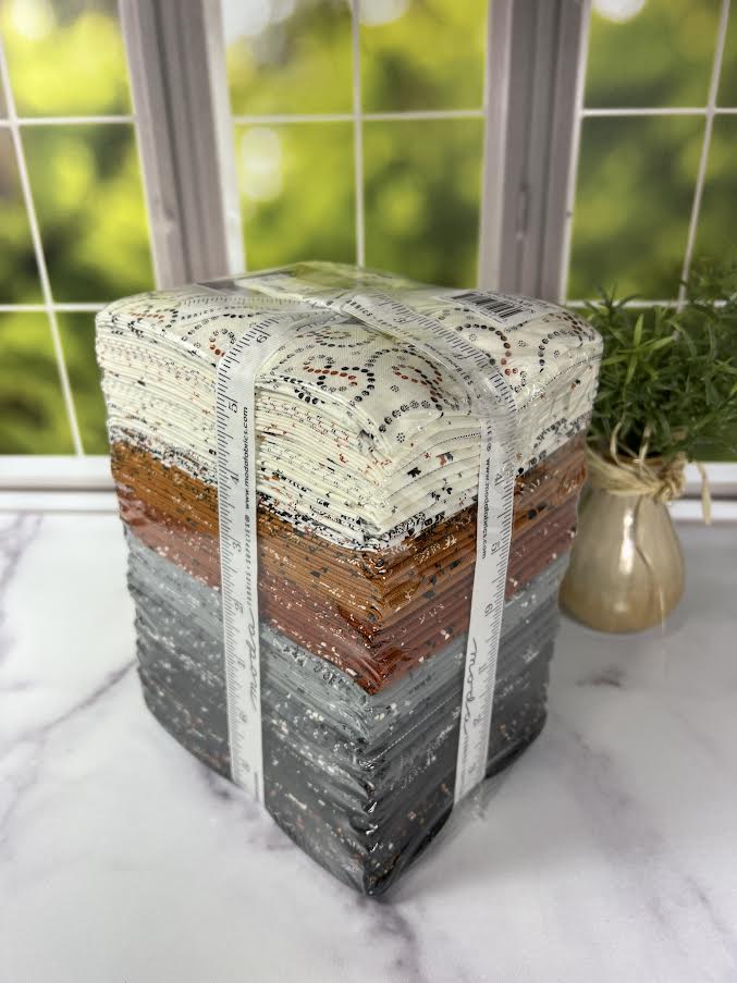 Stack of fabric squares with a measuring tape on a marble surface, blurred greenery in the background