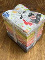 Bundle of fabric fat quarters with floral patterns on a wood display surface at Sewing Bee Studio.