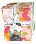 Bundle of floral fabric fat quarters bound with a cloth ruler and Moda designer label, sold by Sewing Bee Studio.