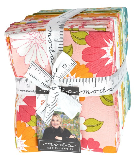 Bundle of floral fabric fat quarters bound with a cloth ruler and Moda designer label, sold by Sewing Bee Studio.